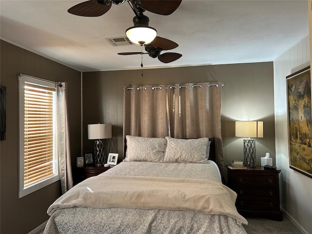 carpeted bedroom with ceiling fan and wood walls