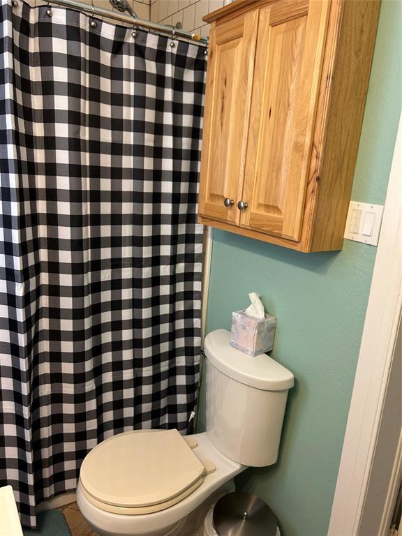 bathroom with a shower with curtain and toilet