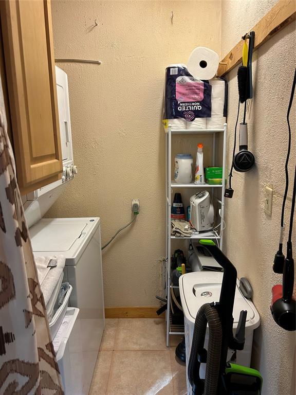 laundry area with cabinets, light tile patterned floors, and washer and clothes dryer