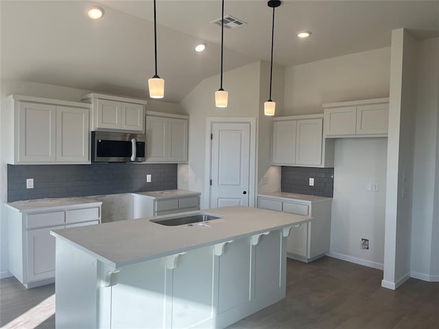 kitchen featuring a center island with sink, light wood-type flooring, hanging light fixtures, and white cabinets