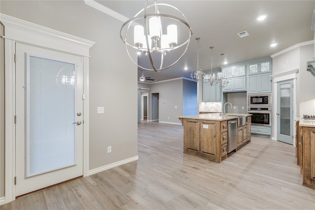 kitchen featuring a kitchen island with sink, ceiling fan with notable chandelier, crown molding, light stone counters, and stainless steel appliances