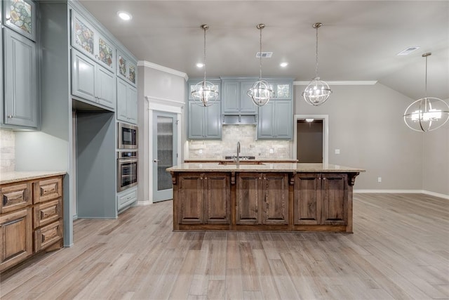 kitchen with hanging light fixtures, stainless steel appliances, crown molding, gray cabinets, and a center island with sink