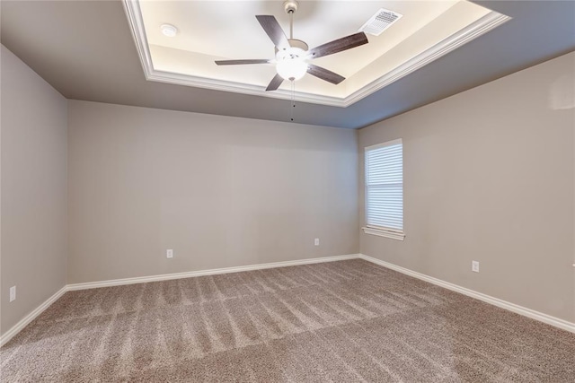 carpeted spare room featuring ceiling fan and a raised ceiling