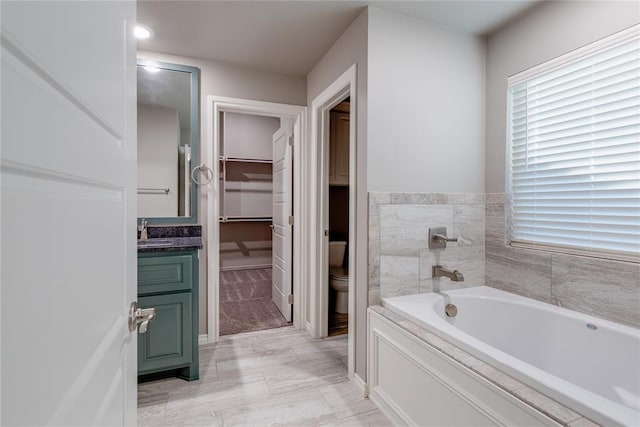 bathroom with vanity, toilet, and a tub