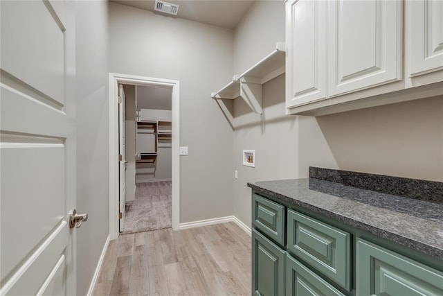 laundry room with light hardwood / wood-style floors, cabinets, and washer hookup