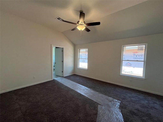 empty room with baseboards, visible vents, dark carpet, a ceiling fan, and lofted ceiling