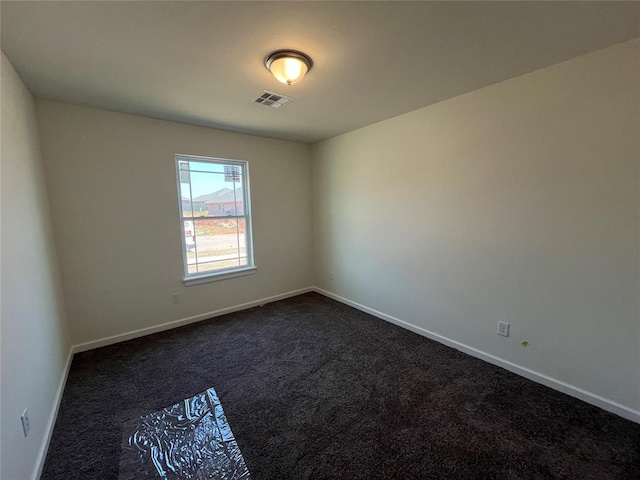 spare room featuring baseboards, visible vents, and dark colored carpet