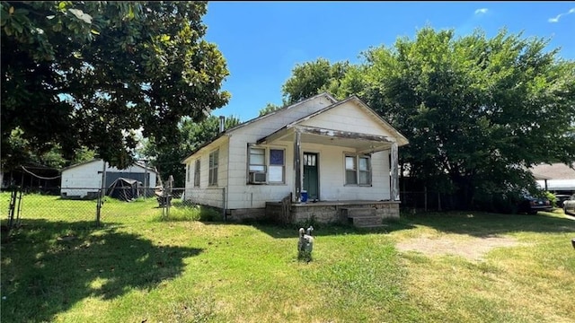 bungalow-style home featuring cooling unit, a porch, and a front lawn