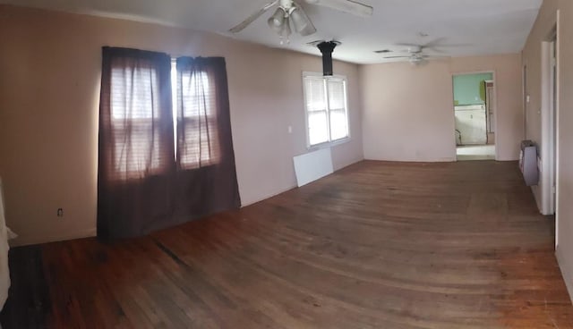 spare room featuring wood finished floors, a ceiling fan, and radiator