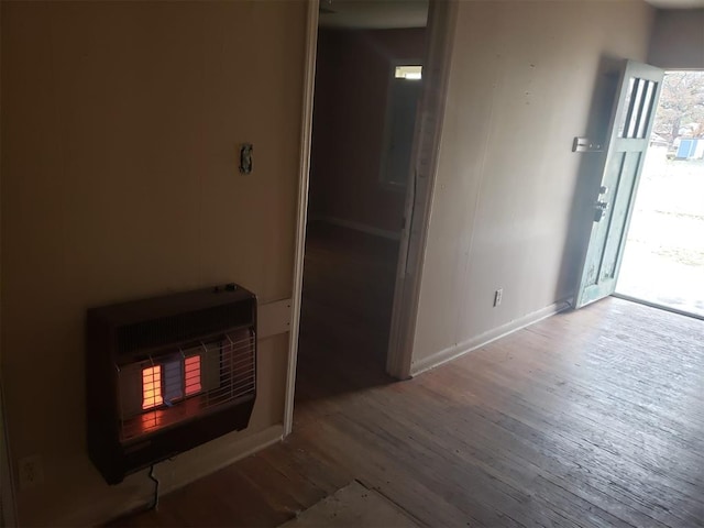 interior space featuring heating unit, baseboards, and wood finished floors