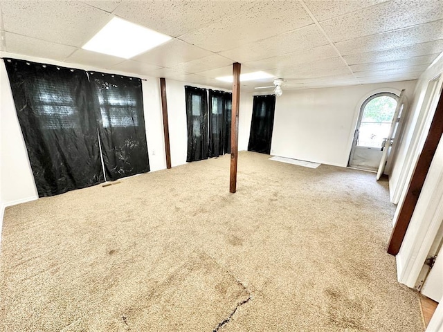 basement with a paneled ceiling, ceiling fan, and carpet floors