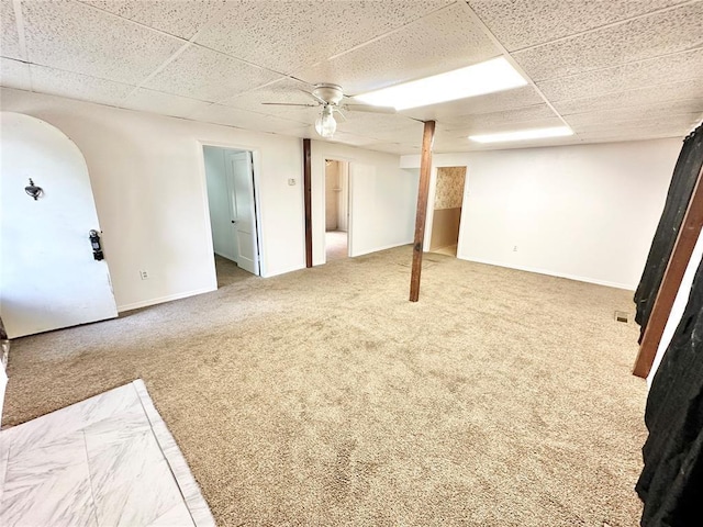 basement with carpet flooring, a paneled ceiling, and ceiling fan