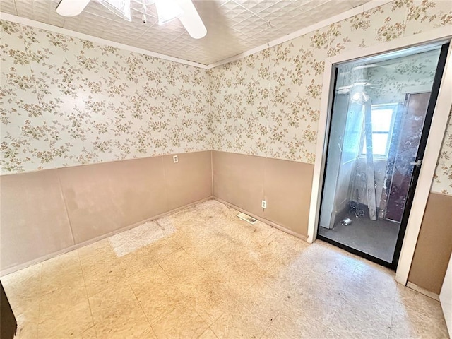 unfurnished room with ceiling fan and ornamental molding