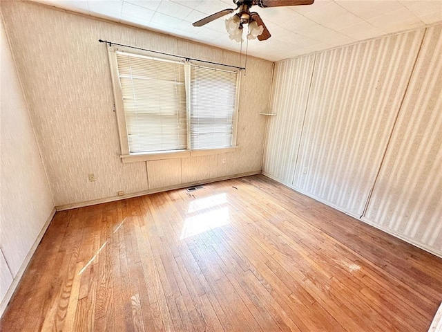 empty room with ceiling fan and hardwood / wood-style floors