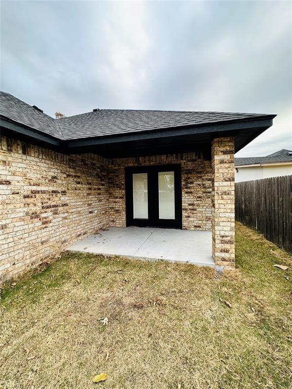 9 SW 24th St, Oklahoma City, OK 73109 - back of property with a shingled roof, a patio area, and brick siding