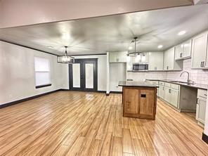 kitchen with white cabinets, pendant lighting, a kitchen island, and sink