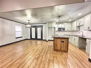 9 SW 24th St, Oklahoma City, OK 73109 - kitchen featuring stainless steel microwave, a center island, light wood-style floors, backsplash, and white cabinetry