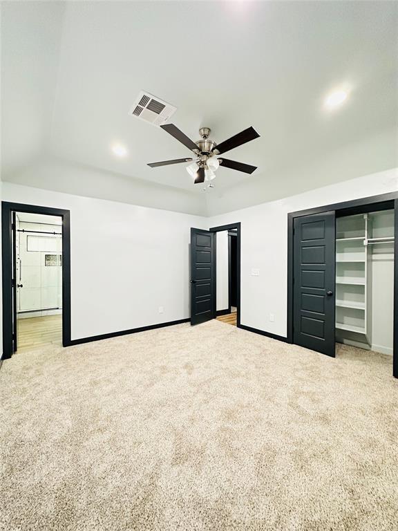 unfurnished bedroom featuring a closet, light colored carpet, and ceiling fan