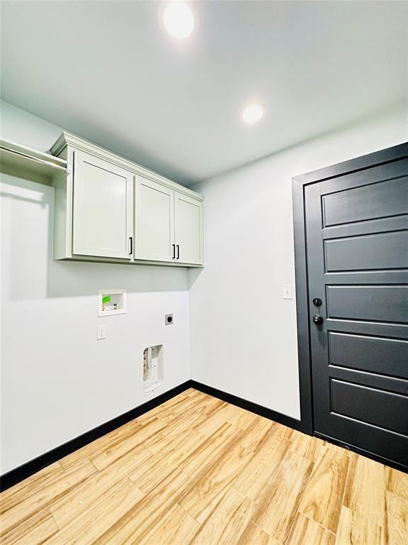 laundry area with hookup for an electric dryer, hookup for a washing machine, light hardwood / wood-style flooring, and cabinets