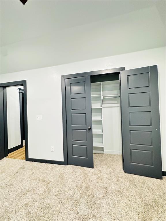 unfurnished bedroom featuring light carpet and a closet