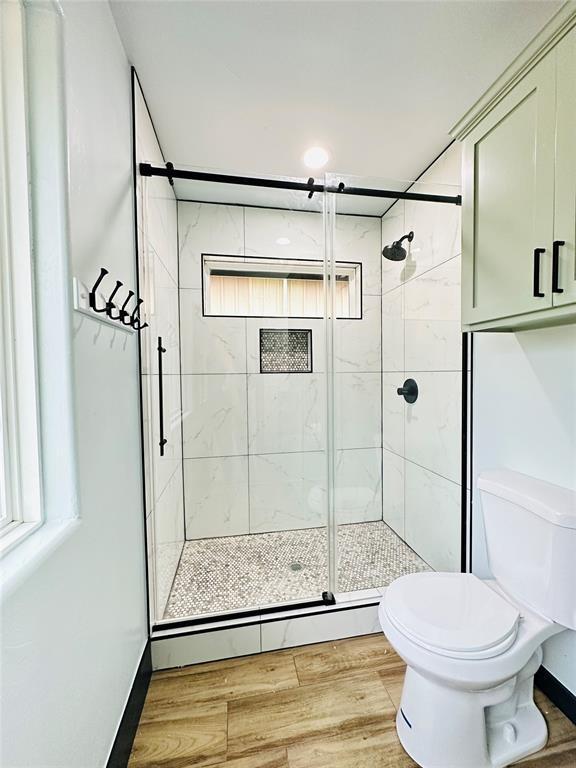 bathroom featuring hardwood / wood-style floors, toilet, a shower with shower door, and baseboard heating