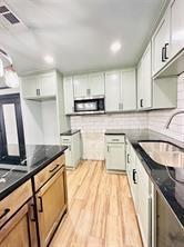 9 SW 24th St, Oklahoma City, OK 73109 - kitchen with stainless steel microwave, dark countertops, light wood-type flooring, decorative backsplash, and recessed lighting