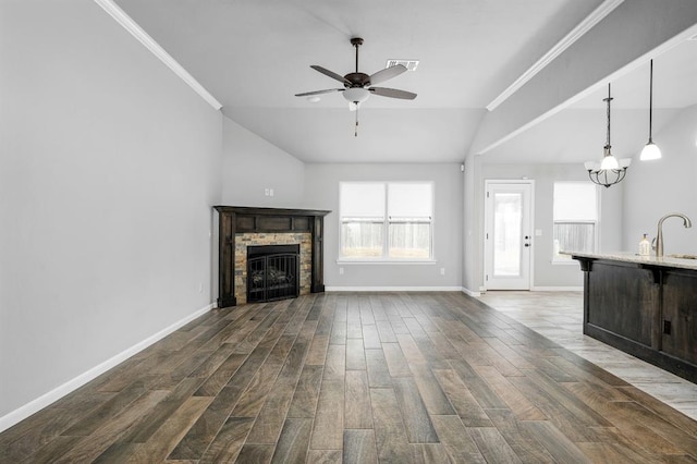 unfurnished living room featuring lofted ceiling, ceiling fan with notable chandelier, sink, crown molding, and a fireplace