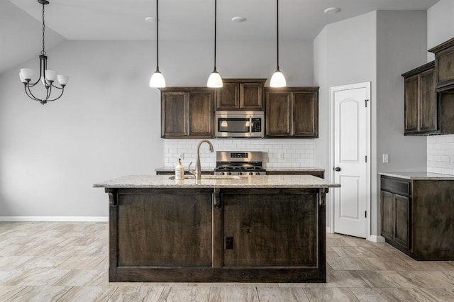 kitchen with dark brown cabinetry, stainless steel appliances, light stone counters, and hanging light fixtures