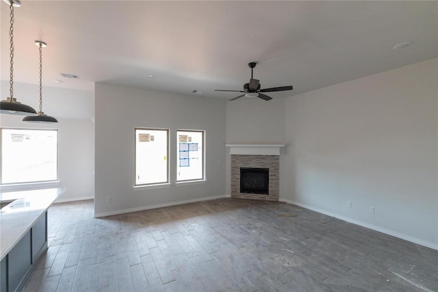 unfurnished living room with wood finished floors, baseboards, and ceiling fan