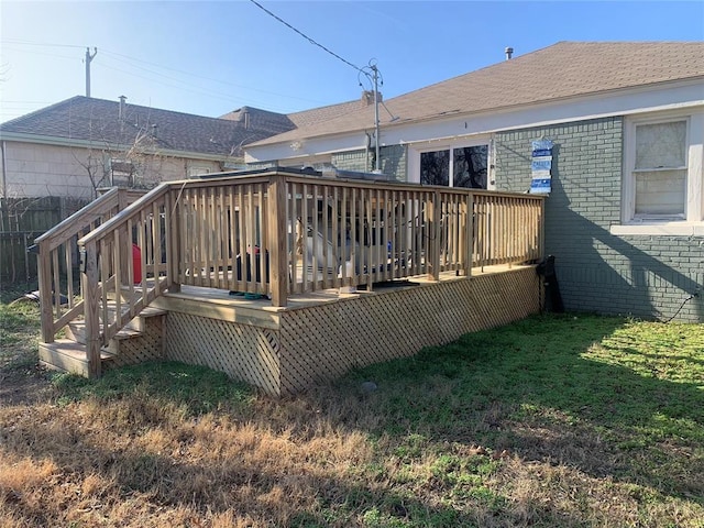 back of property featuring a deck and a lawn