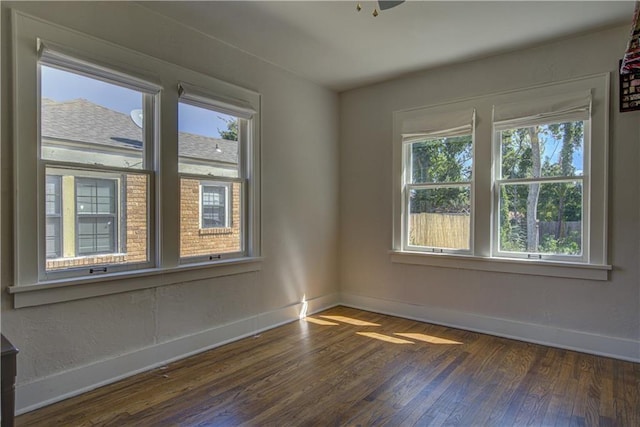 spare room featuring dark hardwood / wood-style floors, a wealth of natural light, and ceiling fan