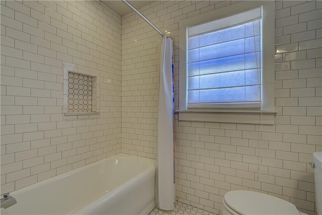 bathroom with tile patterned floors, toilet, tile walls, and shower / tub combo