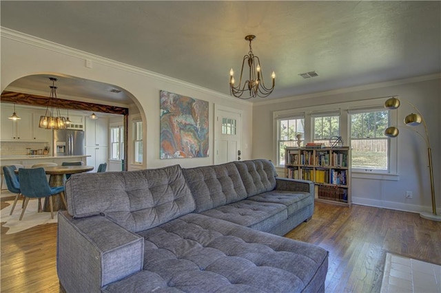 living room with wood-type flooring, a notable chandelier, and ornamental molding