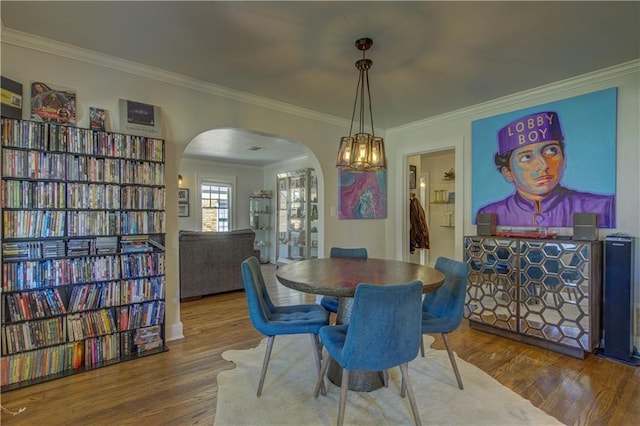 dining space with hardwood / wood-style flooring, an inviting chandelier, and ornamental molding