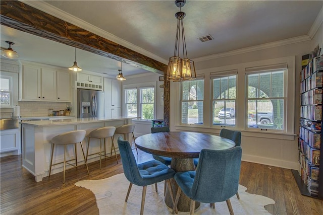 dining space featuring a notable chandelier, ornamental molding, and dark wood-type flooring