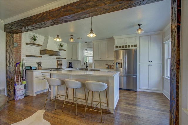 kitchen featuring stainless steel fridge, premium range hood, dark wood-type flooring, decorative light fixtures, and white cabinetry