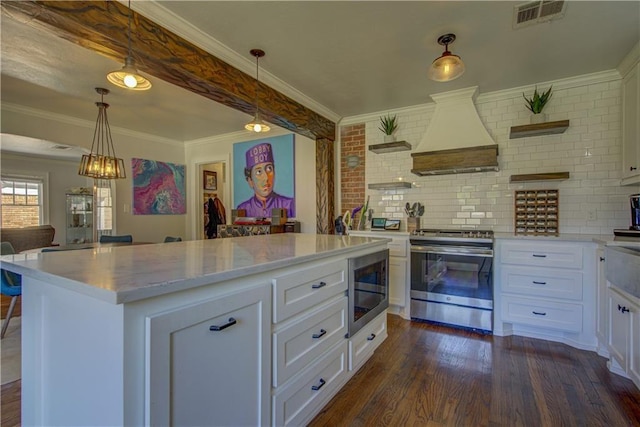 kitchen with white cabinets, stainless steel appliances, custom range hood, and a kitchen island