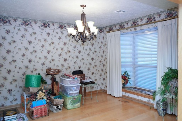 dining room with hardwood / wood-style floors, a chandelier, and a textured ceiling