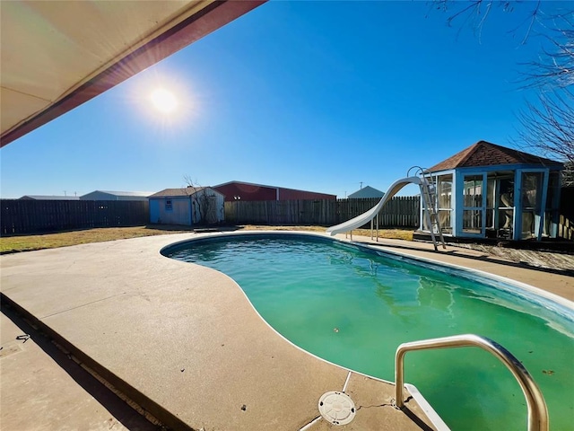 view of pool featuring a patio area, a storage unit, and a water slide