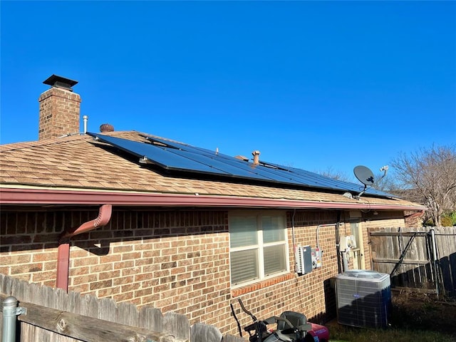 view of property exterior with central AC unit and solar panels