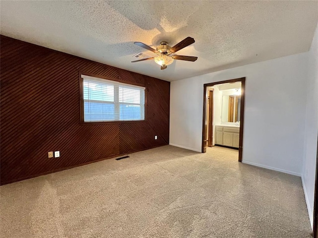 carpeted spare room with ceiling fan, wooden walls, and a textured ceiling