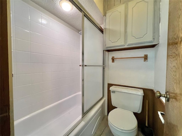 bathroom featuring toilet, enclosed tub / shower combo, and a textured ceiling