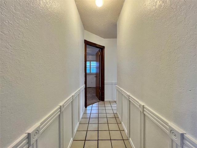 corridor with light tile patterned flooring and a textured ceiling