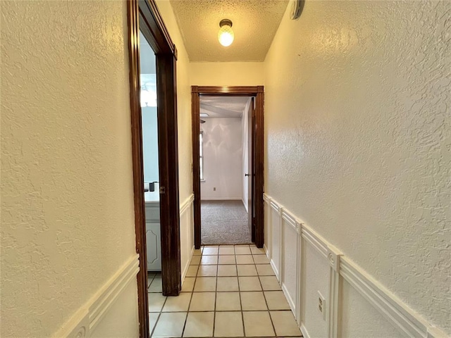 hall with a textured ceiling and light tile patterned flooring