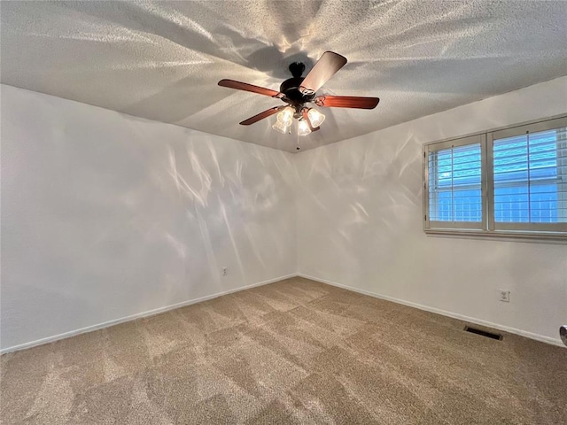 carpeted spare room featuring ceiling fan and a textured ceiling