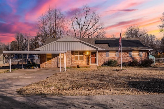 ranch-style house with solar panels and a carport