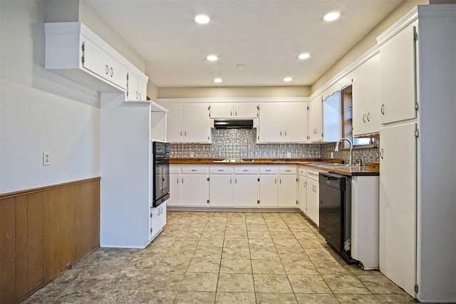 kitchen with white cabinets, sink, wooden walls, and black appliances