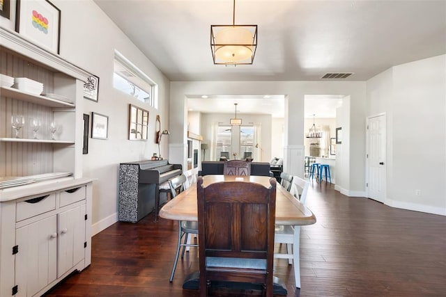 dining room with dark hardwood / wood-style floors, a healthy amount of sunlight, and an inviting chandelier