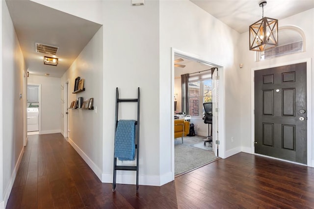 entryway with dark hardwood / wood-style floors, an inviting chandelier, and washer / clothes dryer