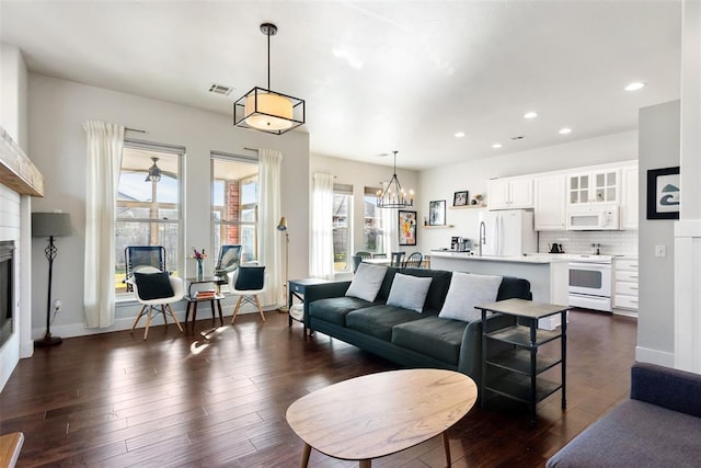 living room with dark hardwood / wood-style flooring and an inviting chandelier